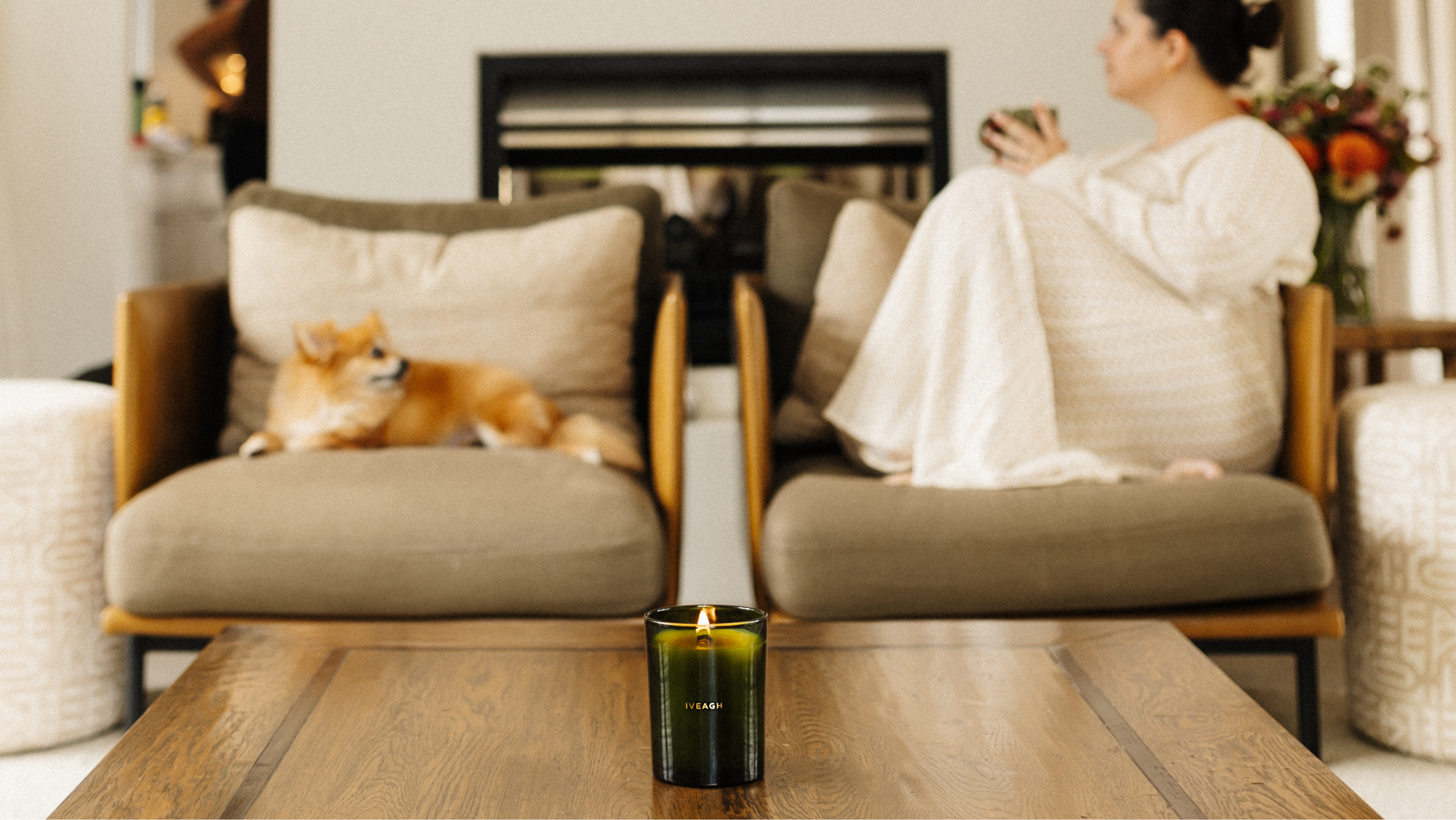 Woman sitting on a couch with a dog, holding a cup, in a cozy living room.